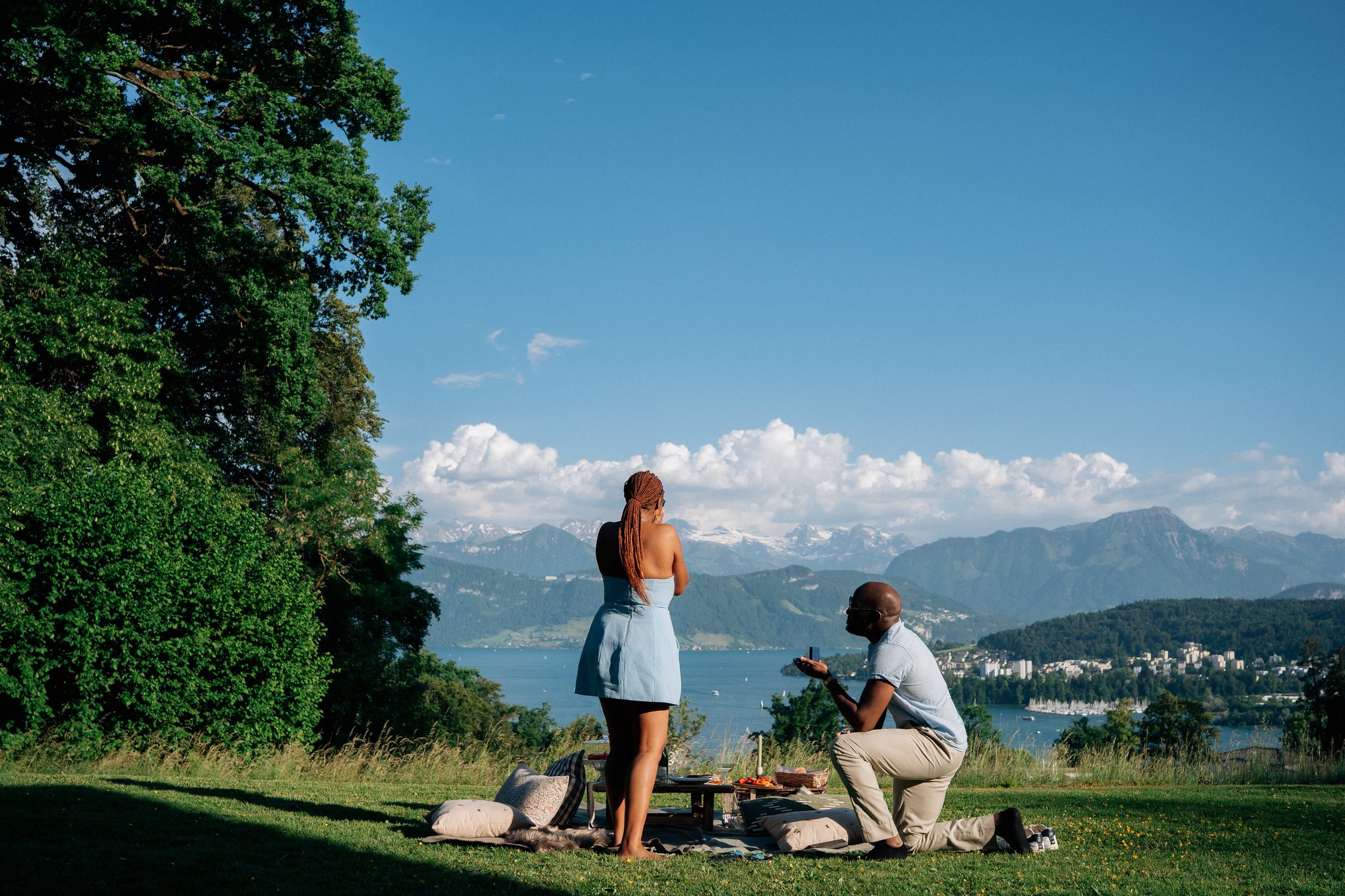 Adetunji on one knee proposing to Sally above Lake Lucerne